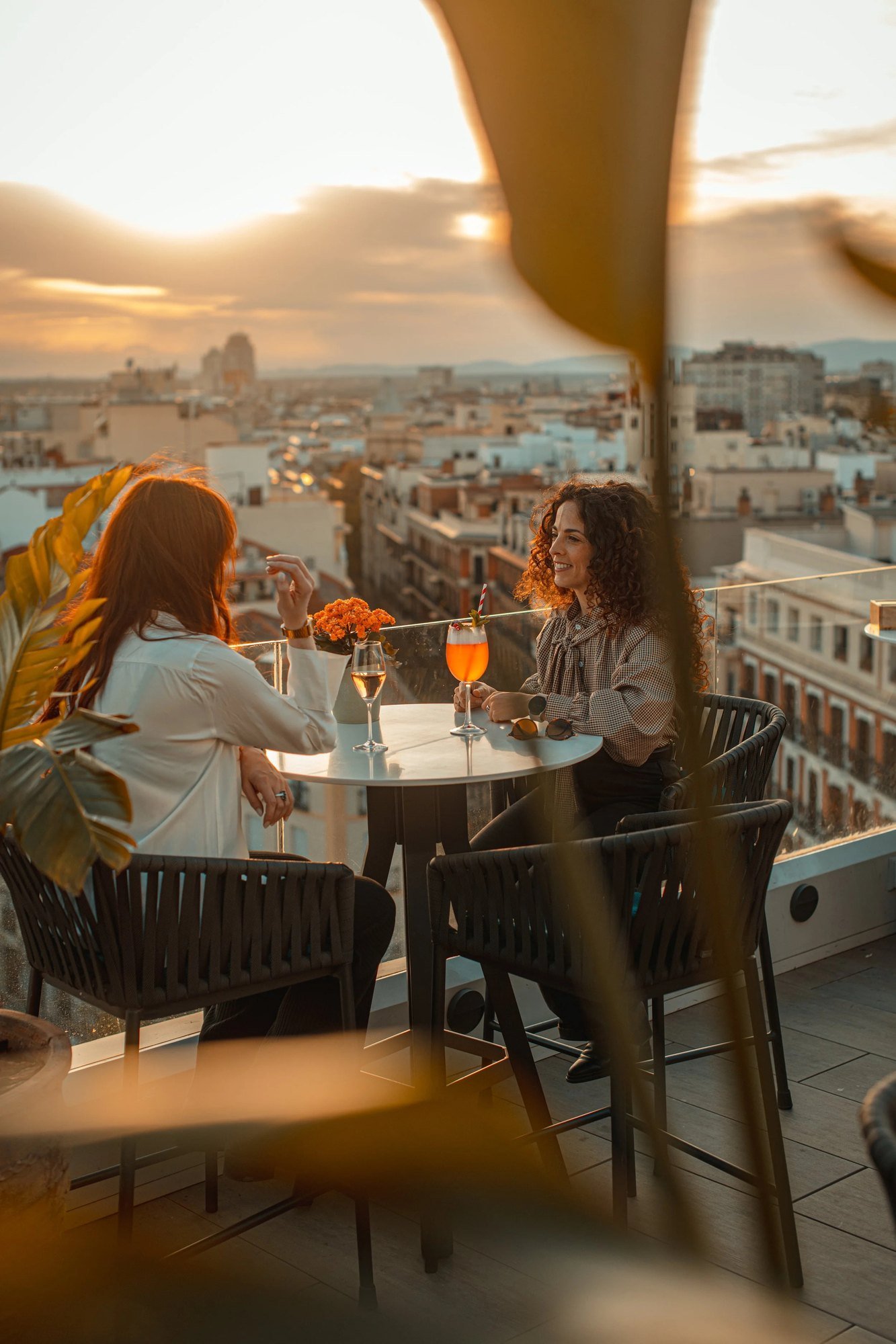Dos amigas contemplando las luces de la ciudad desde una terraza al anochecer