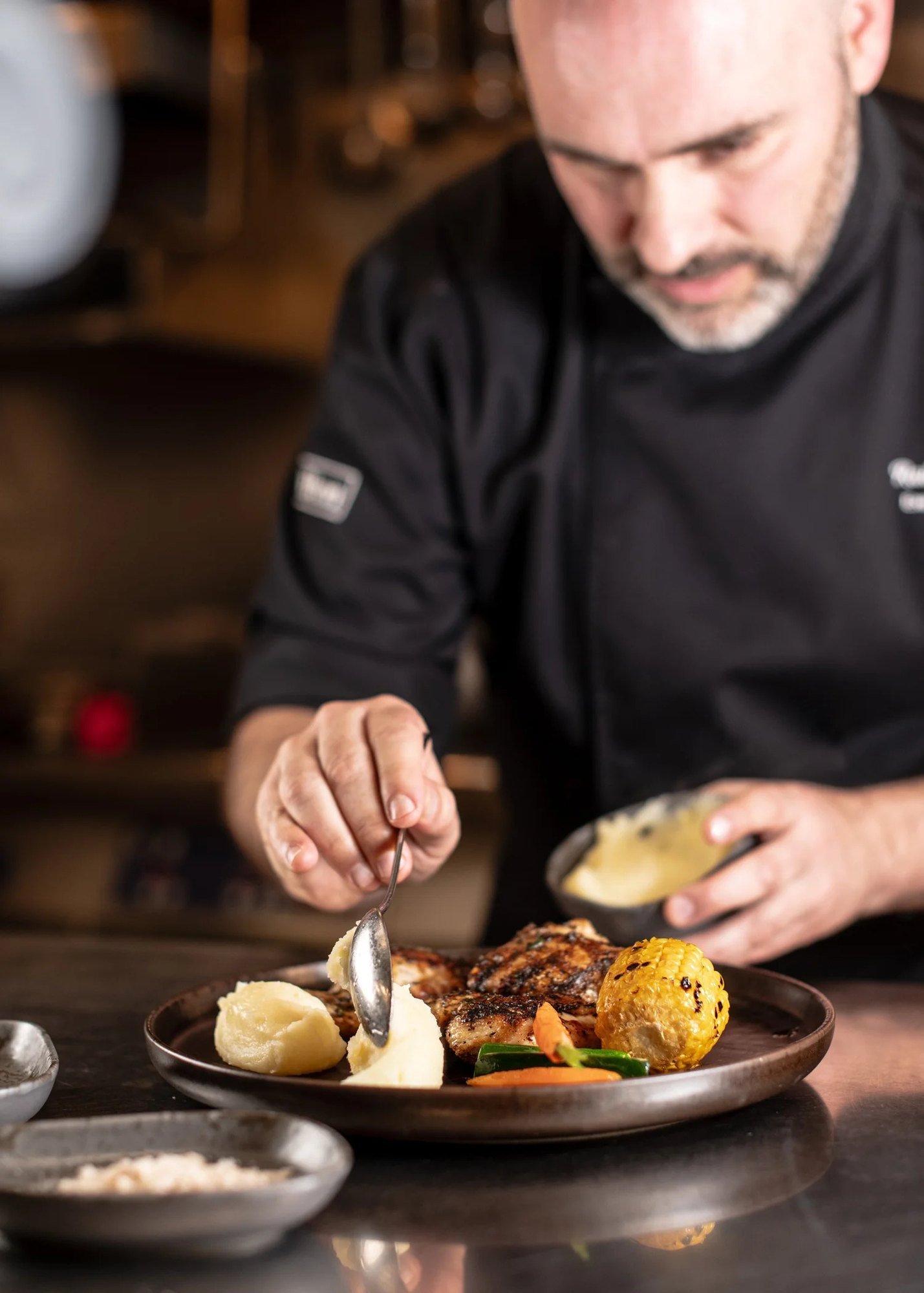 Chef sirviendo un plato recién emplatado a una pareja sentada a la mesa