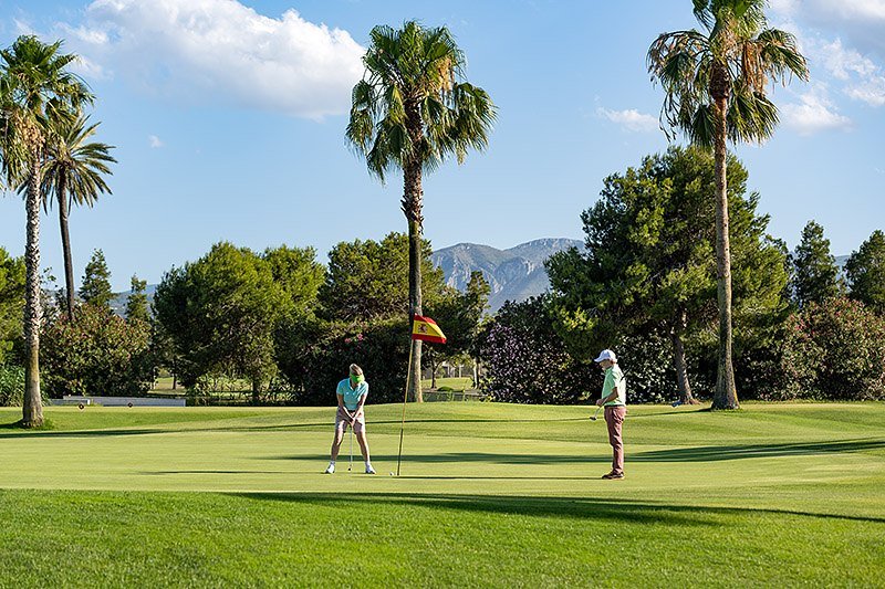 Pareja de huéspedes jugando al golf en el campo cercano al hotel